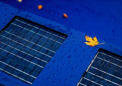 Chez-Elizabeth-et-Jacques-5 Panneau solaire bleu avec gouttes d'eau et feuille jaune posée dessus, sur fond bleu.