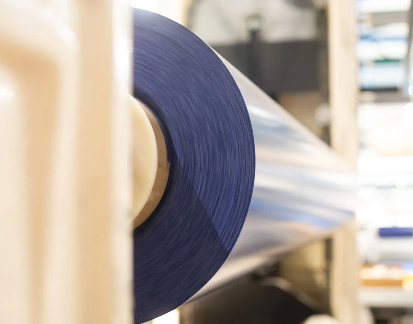 COVERSEAL-entreprise-3 Rouleau de film plastique bleu enroulé sur une machine industrielle dans un environnement de production clair.