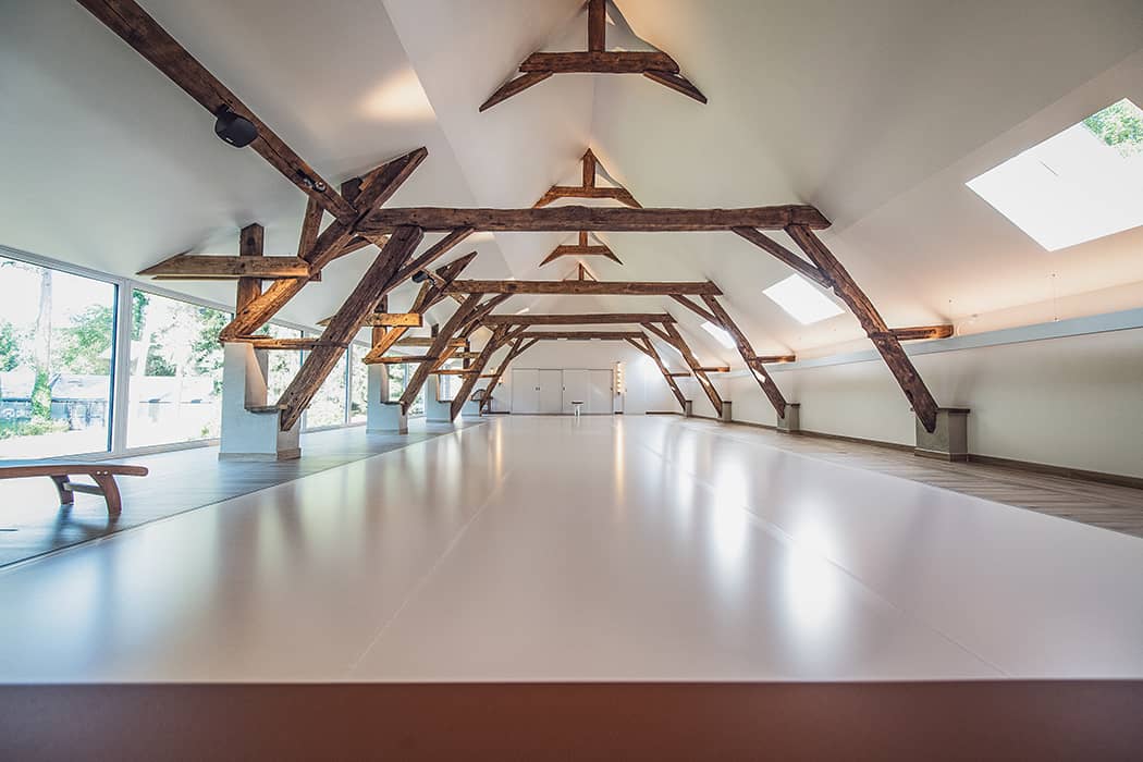 PISCINE-INTERIEURE (1) Plafond avec poutres en bois apparentes dans une grande pièce lumineuse avec piscine intérieure couverte et fenêtres panoramiques.