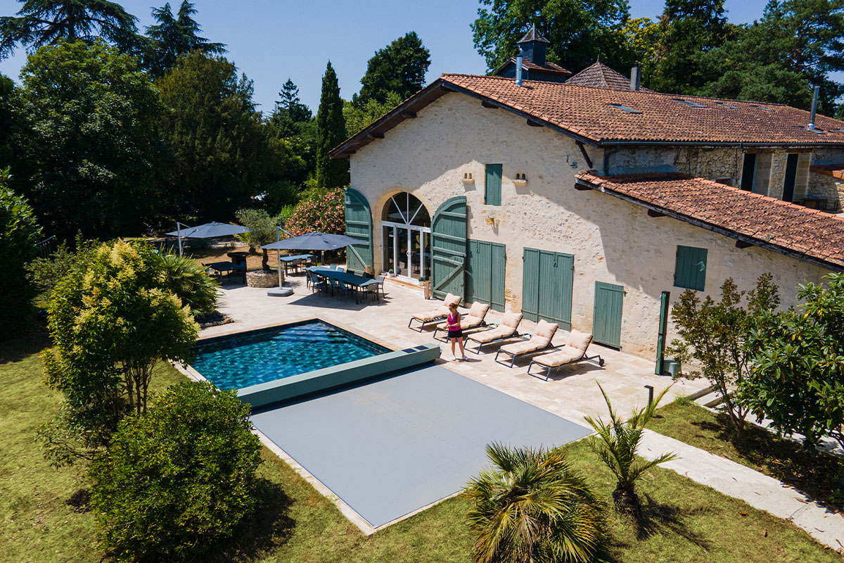 Sequoia Vue aérienne d’une maison en pierre avec piscine équipée d’une couverture Coverseal grise, intégrée harmonieusement dans la terrasse en pierre claire.
